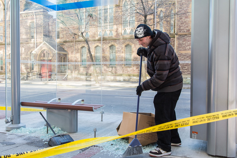 Sweeping broken glass from a bus shelter
