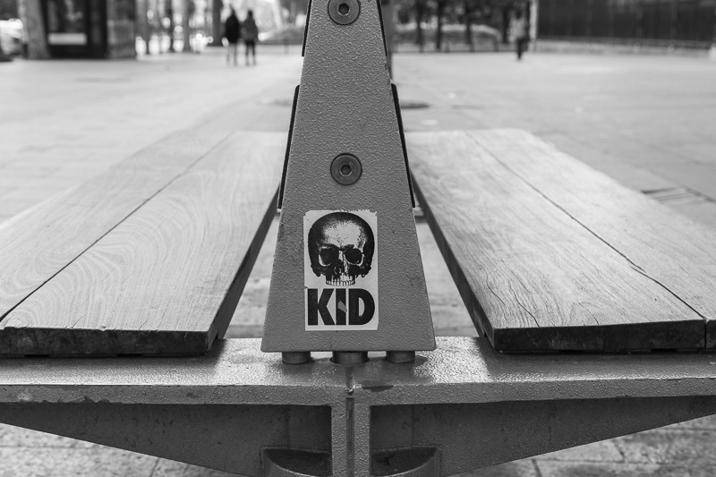 Graffiti sticker of skull on side of bench