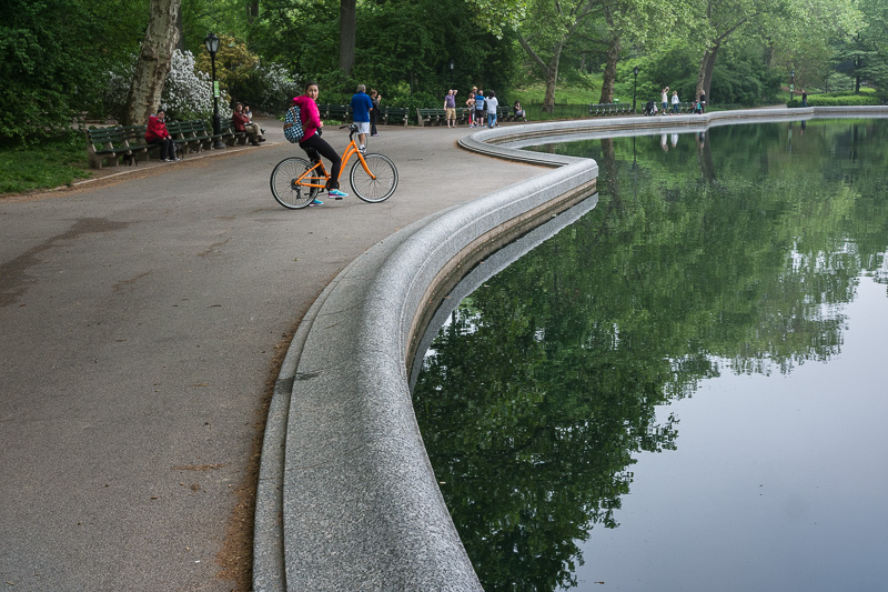Cyclist pauses by the Conservatory Water in Central Park.