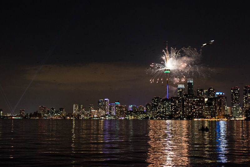 Plane comes in for landing as fireworks explode from the CN Tower.