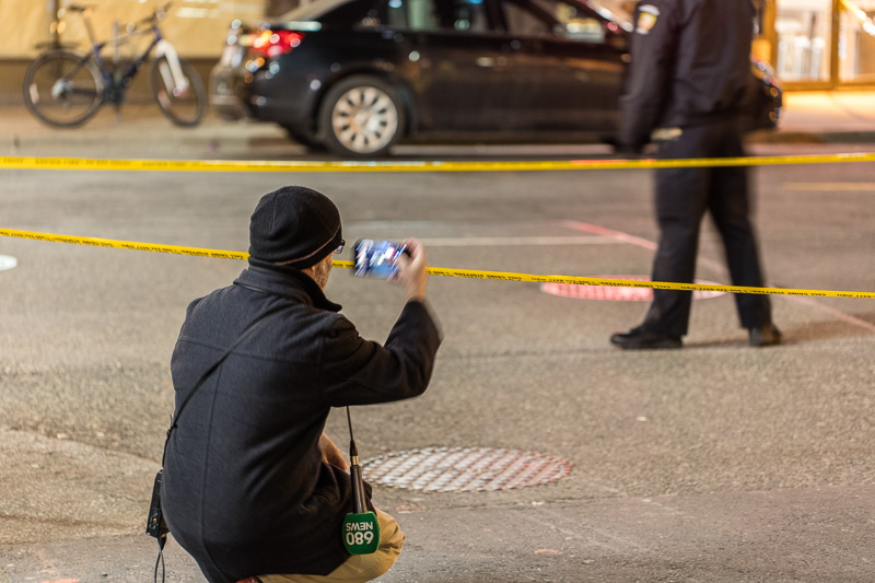 Bystander using cell phone to take a photo of the crime scene