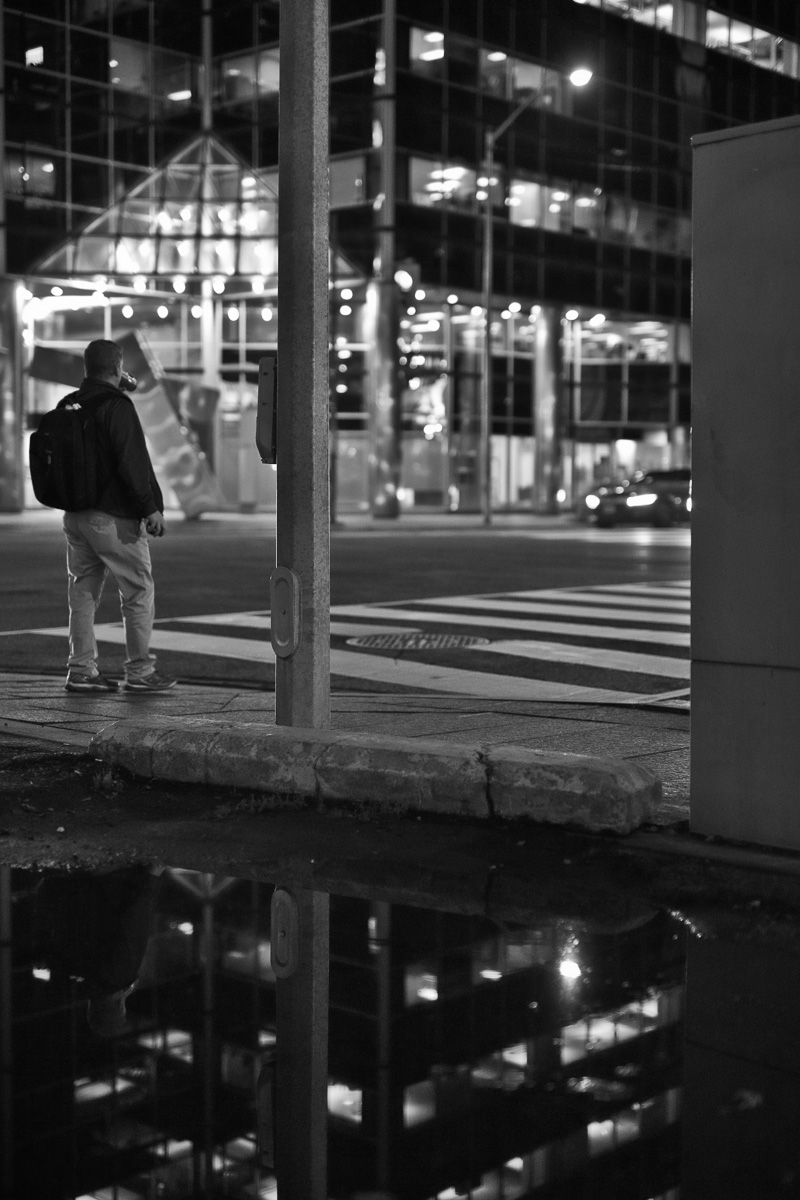 Man reflected in puddle at Church/Bloor intersection, Toronto 