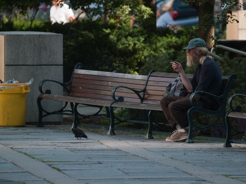 Homeless man sitting in park west of Roy Thomson Hall