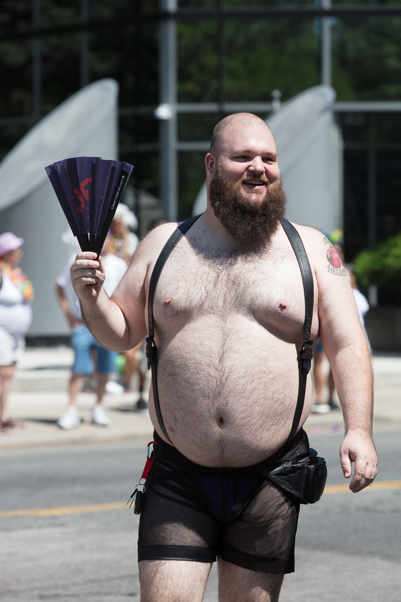man wearing shorts and suspenders and carrying a fan