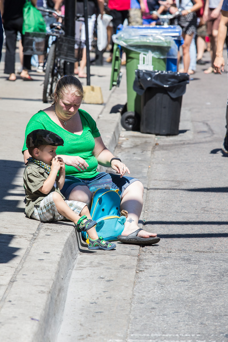 Woman and child sit on curb eating