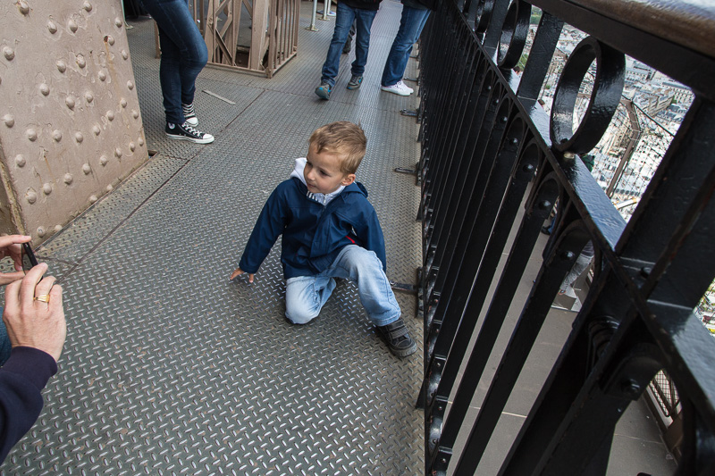 Child on the Eiffel Tower posing for an iPhone