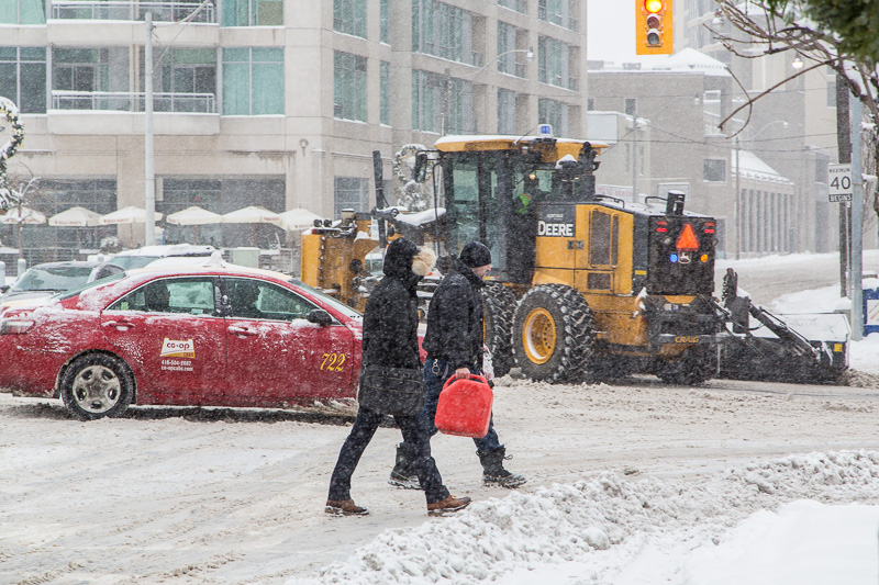 Pedestrians carry red gas can through the snow