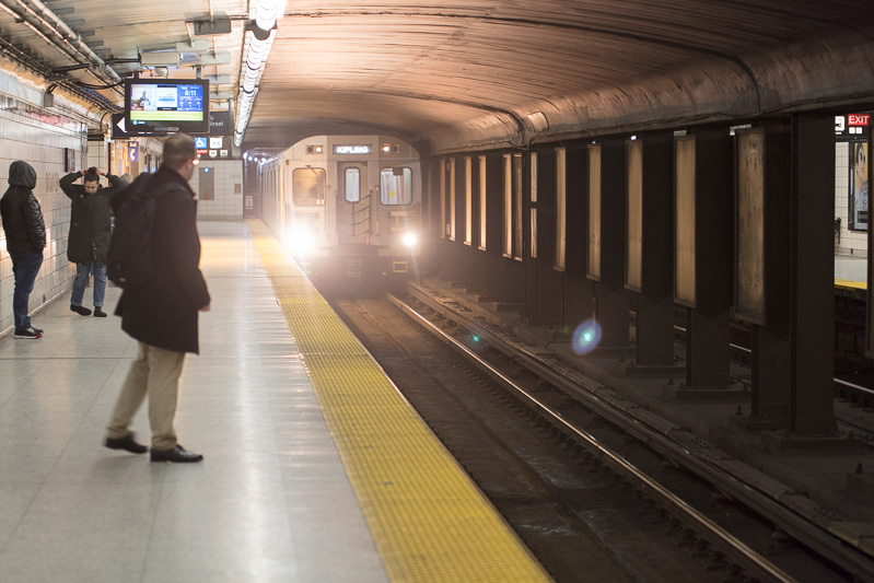 Man waits on platform as subway arrives