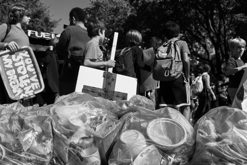 Protesting children pass bags of garbage left by an adult-owned food truck