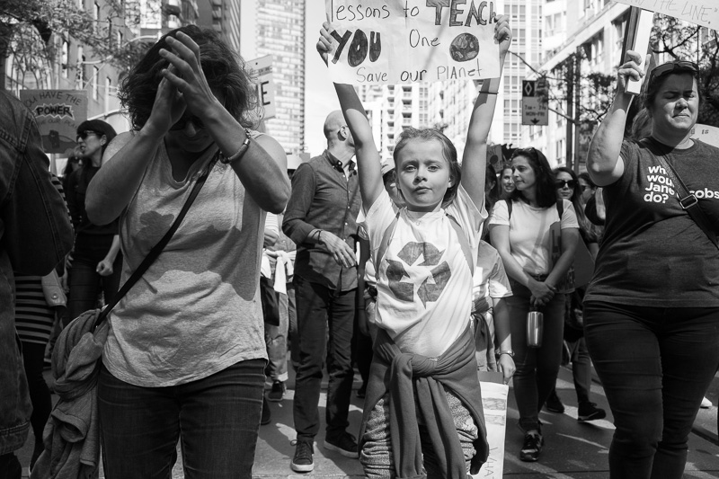 Young girl marches down Bay Street carrying a sign