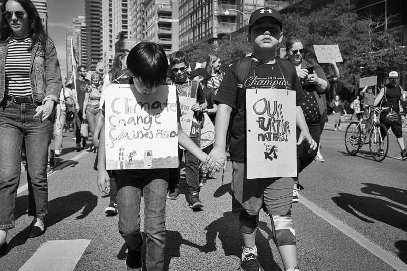 Two young boys hold hands during the climate strike march down Bay Street, Toronto