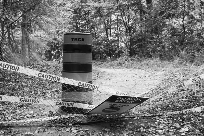 Caution tape and a temporary fence block the path along Yellow Creek, in Toronto