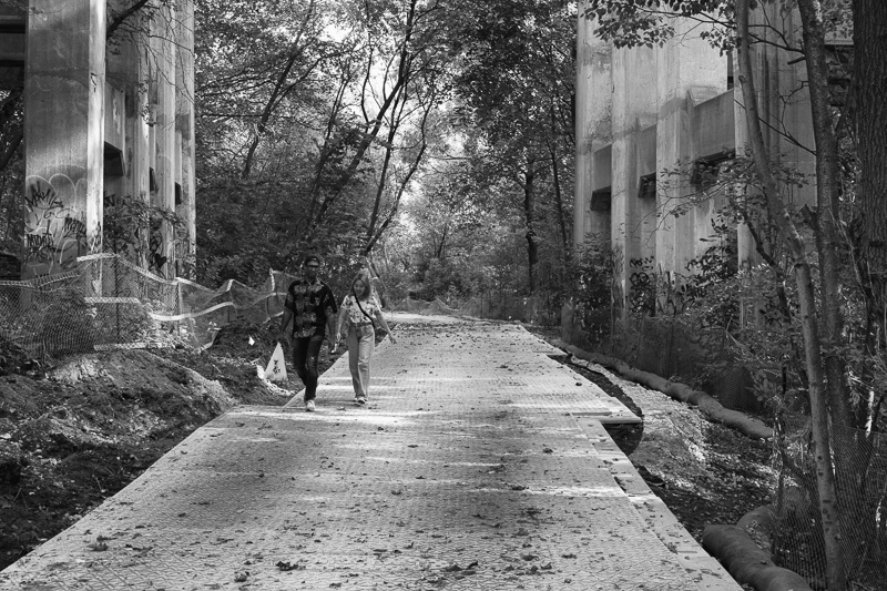 A couple walk holding hands in the construction zone, Yellow Creek, Toronto