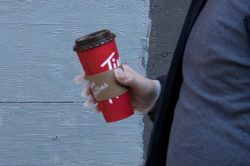 Photograph of hand in plastic glove holding coffee cup - detail