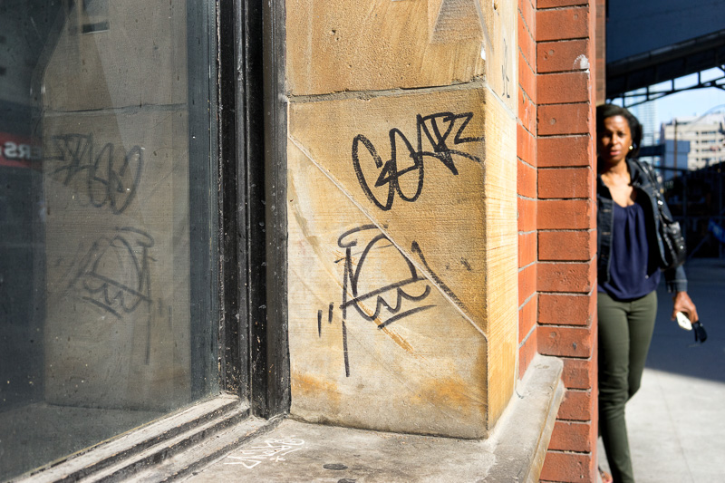 Woman rounds a corner past graffiti tagging.
