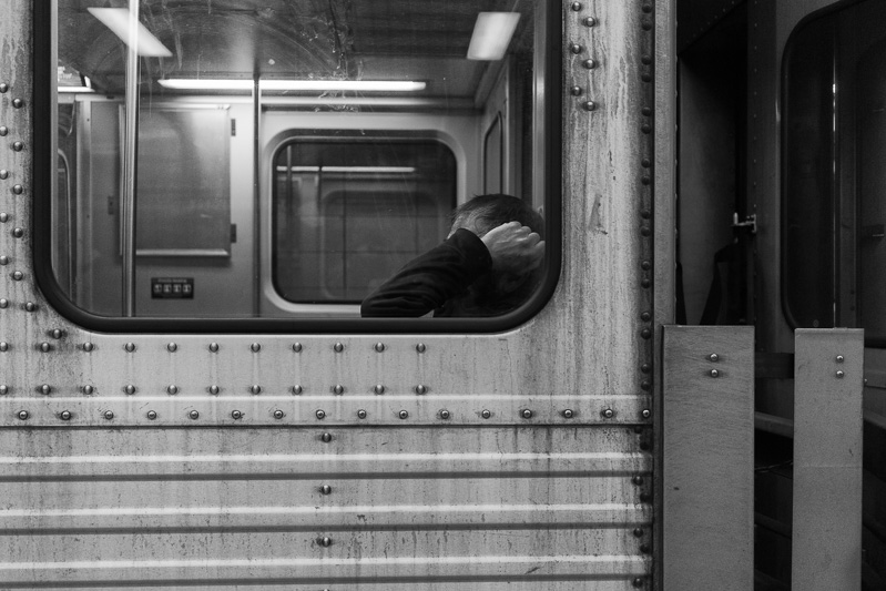 Man leaning against a subway window.