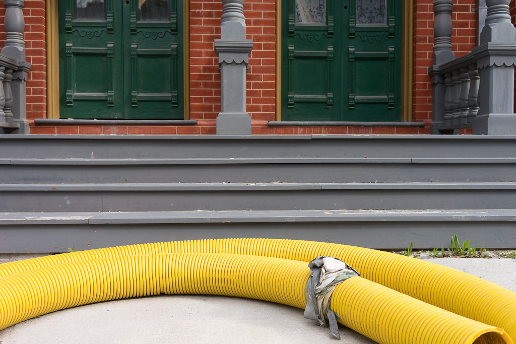 Curved yellow tubing laid out at the front steps of a duplex entrance.