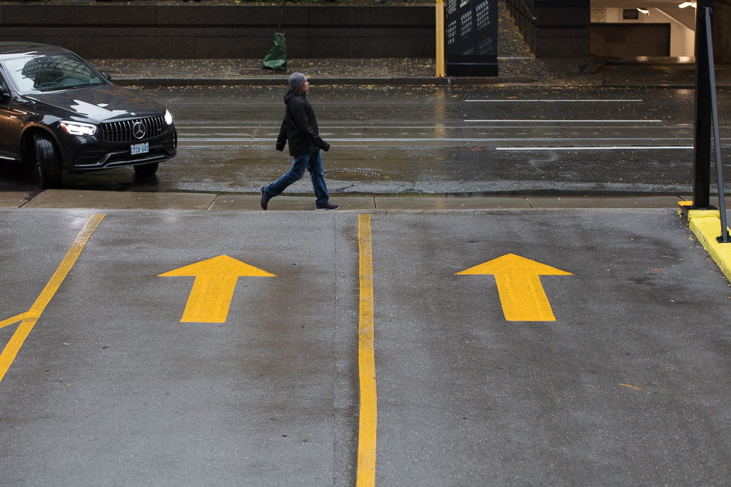 Two yellow arrows on wet pavement.