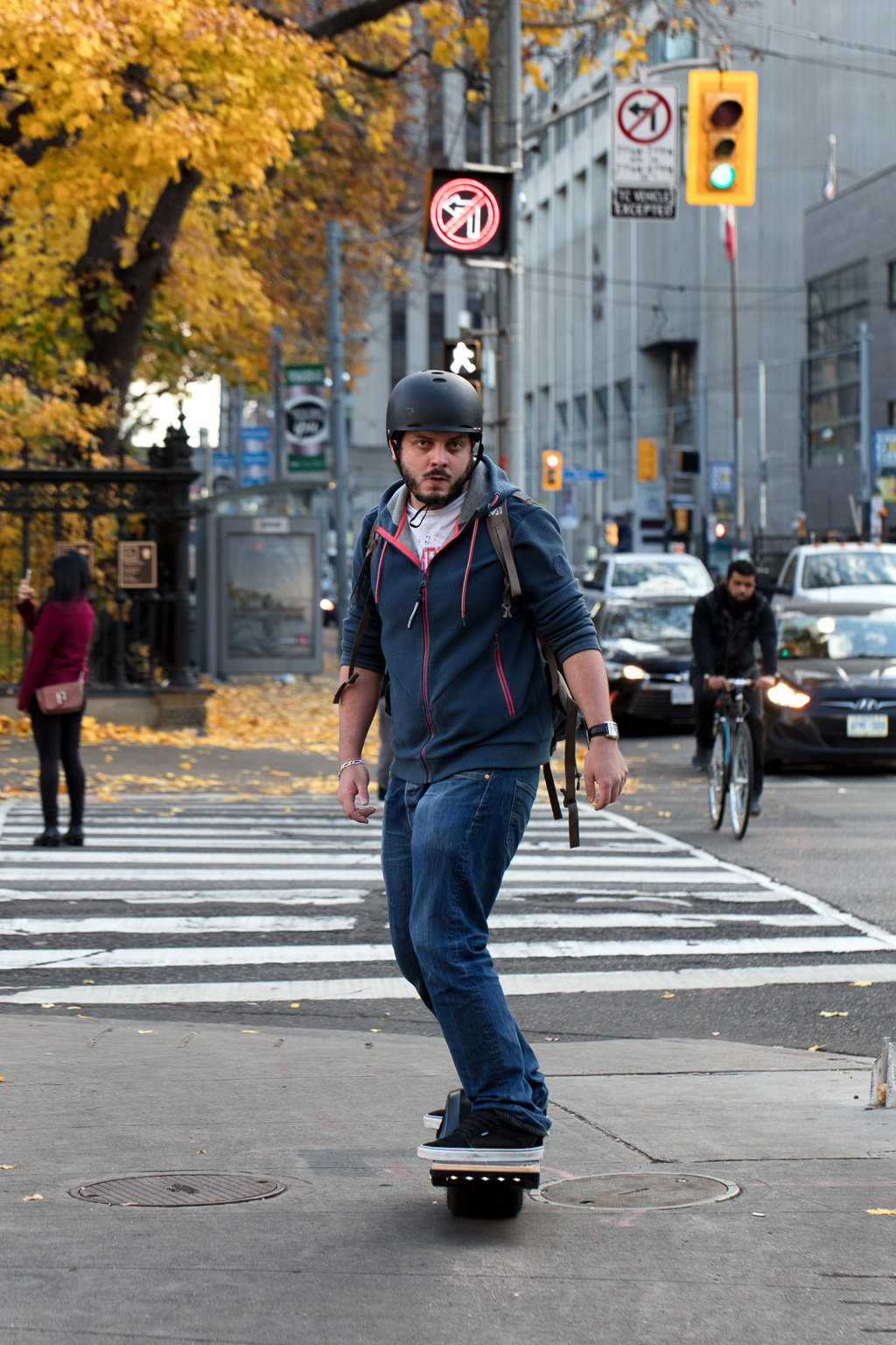 Young man rides board across University Avenue on Queen West in Toronto.