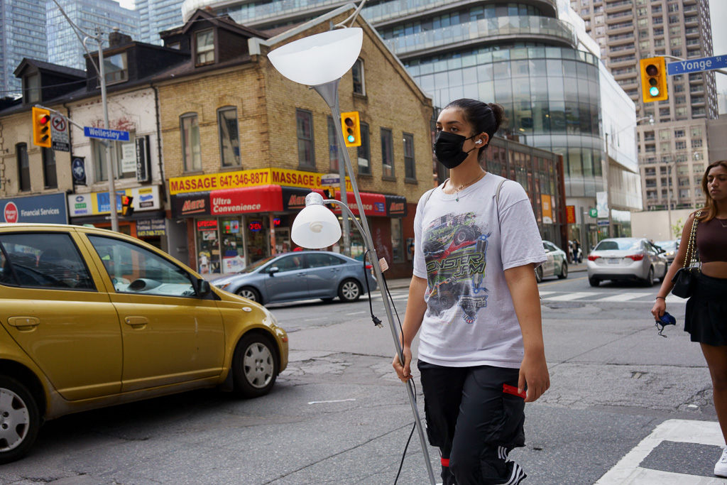 Woman with lamp crosses Yonge Street at Wellesley, Toronto