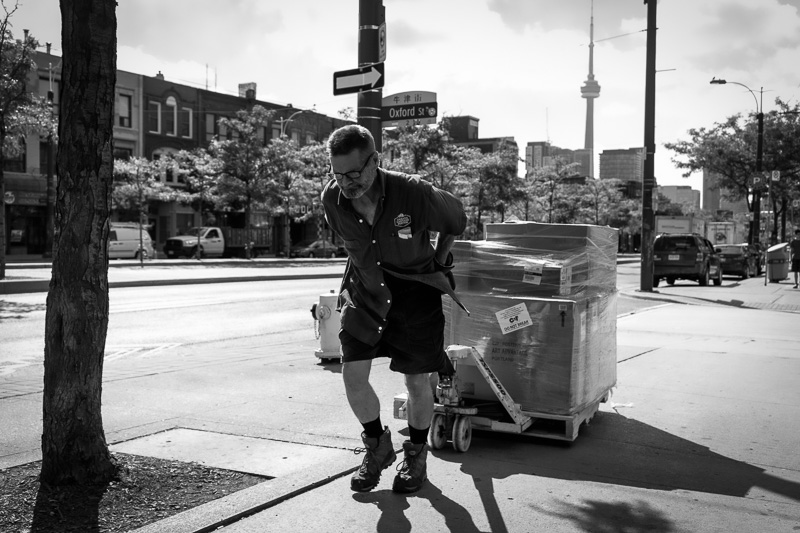 Delivery man pulls boxes on hand truck in Toronto's Chinatown