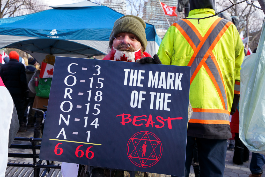 Protester at Anti-Vaxx Rally carries sign claiming that Corona is the mark of the Beast