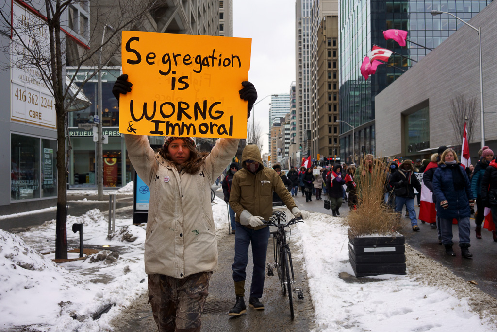 Anti-vaxx protester holds up sign which says: "Segregation is worng & immoral."