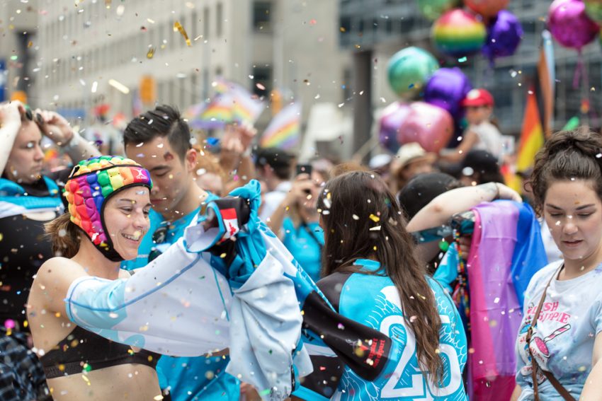 People celebrate Pride on Toronto's Bloor Street while glitter settles all around them.